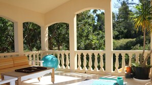 A sunlit patio with a wooden table, a blue exercise ball, and a patterned rug. - Tranquil Mallorca Villa Seaside Getaway with Pool (IB)