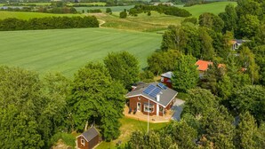 A large house with a solar panel roof, surrounded by lush green fields and trees. - "Swipdagh" - 150m from the sea by Interhome (Martofte)