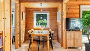 A wooden cabin interior with a dining table, chairs, a television, and a bookshelf. - "Swipdagh" - 150m from the sea by Interhome (Martofte)