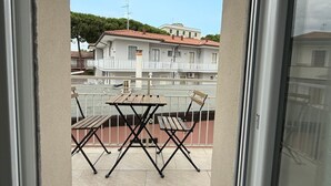 Un balcon avec une table et des chaises, une balustrade et une vue sur un immeuble avec un toit rouge.