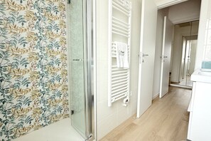 Un baño moderno con ducha, toallero y puerta de cristal.
