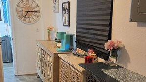 Una cocina con armarios de madera, un reloj y una ventana con persianas.