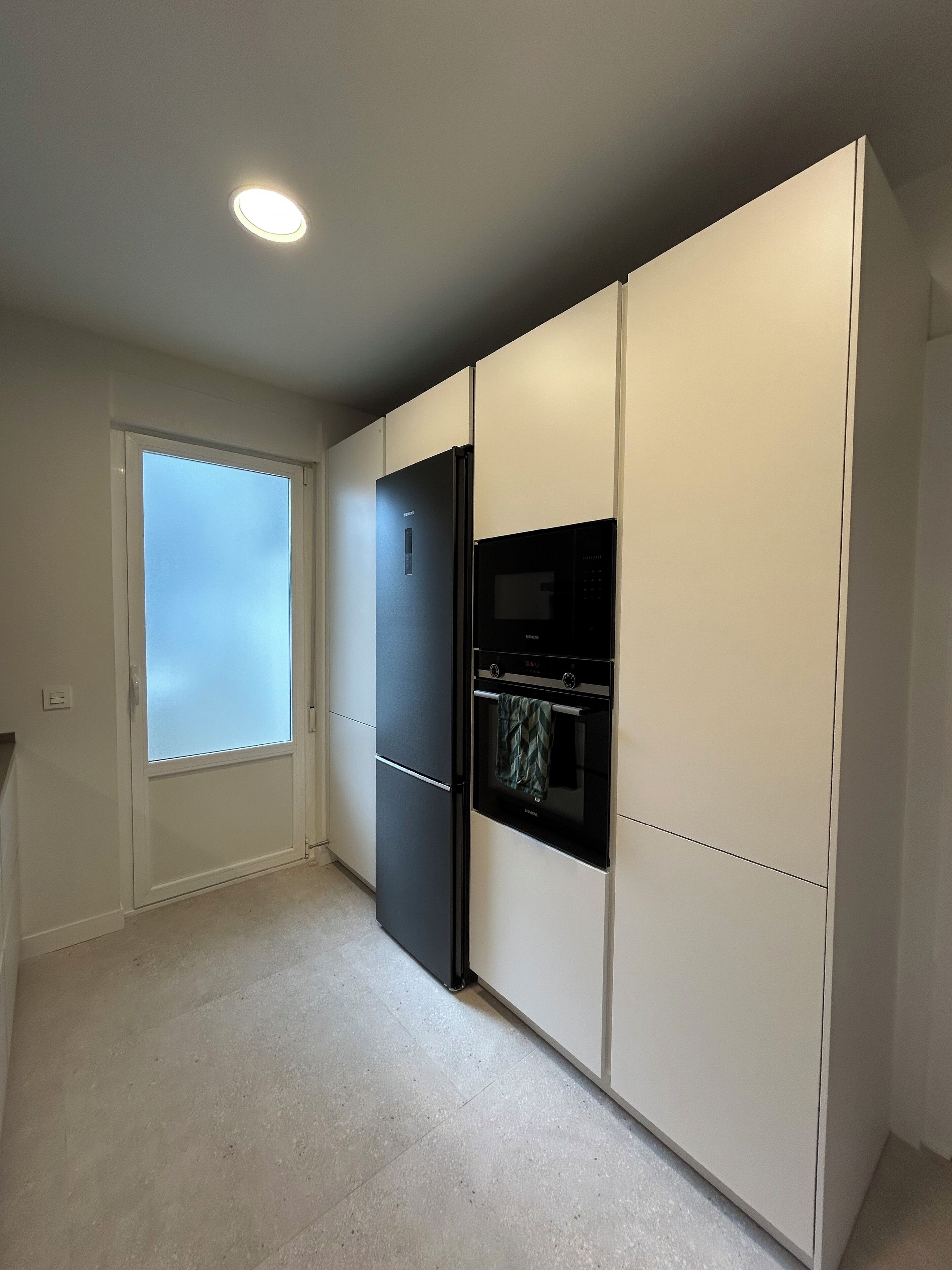 A modern kitchen with a built-in refrigerator, oven, and microwave.