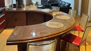 Une cuisine moderne avec un îlot central aux lignes courbes, un coin repas doté d’une table ronde et un canapé en cuir noir.