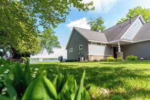 A house with a sloped roof, a front porch, and a view of a lake.