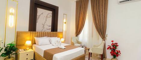 A hotel room with a bed, bedside lamps, a nightstand, a potted plant, a chair, and a vase with flowers.