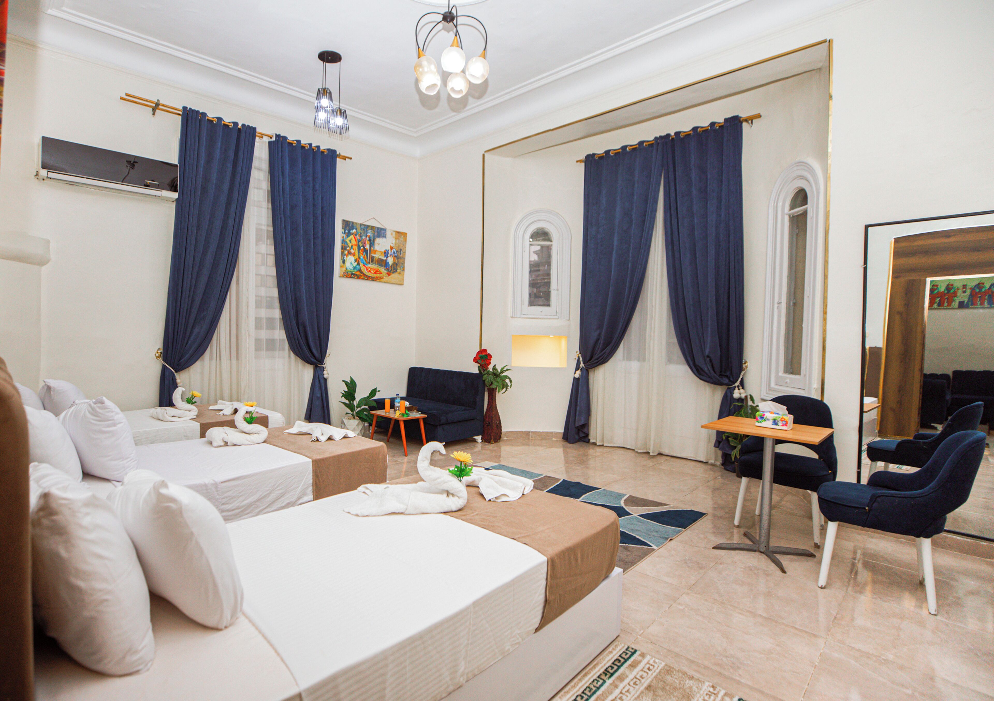 Una habitación de hotel con dos camas, un escritorio, una silla, una mesita y un espejo.