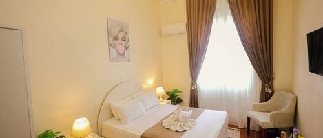 A neatly arranged bedroom with a bed, bedside lamps, a chair, a desk, and a plant.