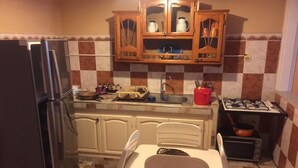 Eine kompakte Küche mit Kühlschrank, Spüle, Herd und einem Essbereich mit Tisch und Stühlen.