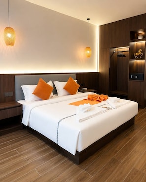 Ein modernes Hotelzimmer mit einem großen Bett, zwei Nachttischen, einem Schrank und einem Schreibtisch mit Stuhl.