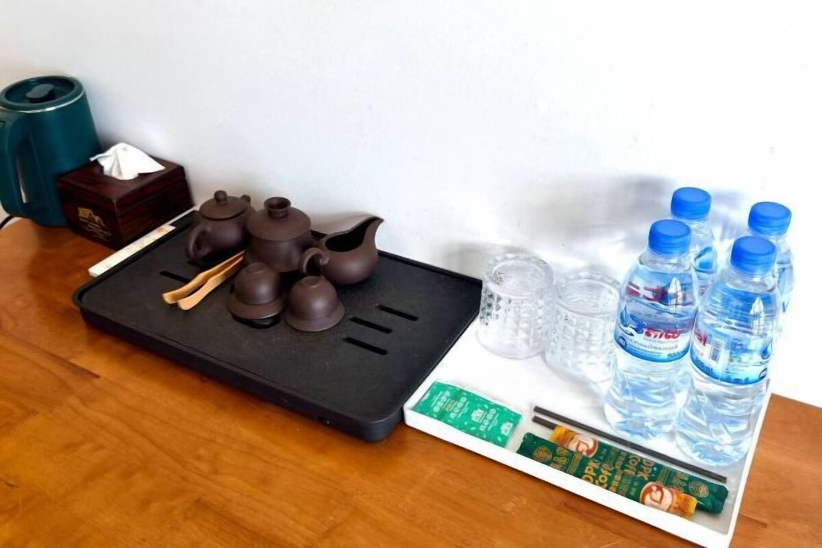 A tray with tea utensils, water bottles, a tissue box, and a teapot on a wooden table.