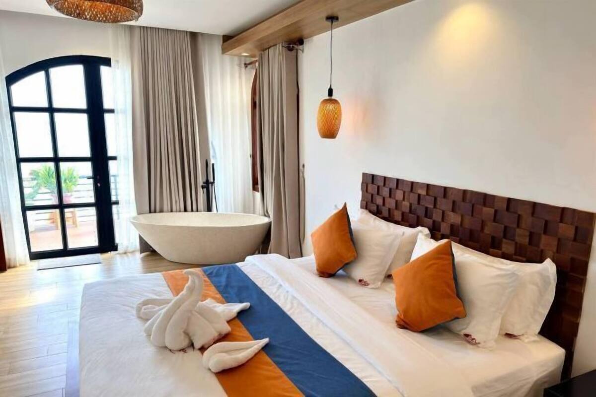 A hotel room with a large bed, a bathtub, and a view of the outdoors.
