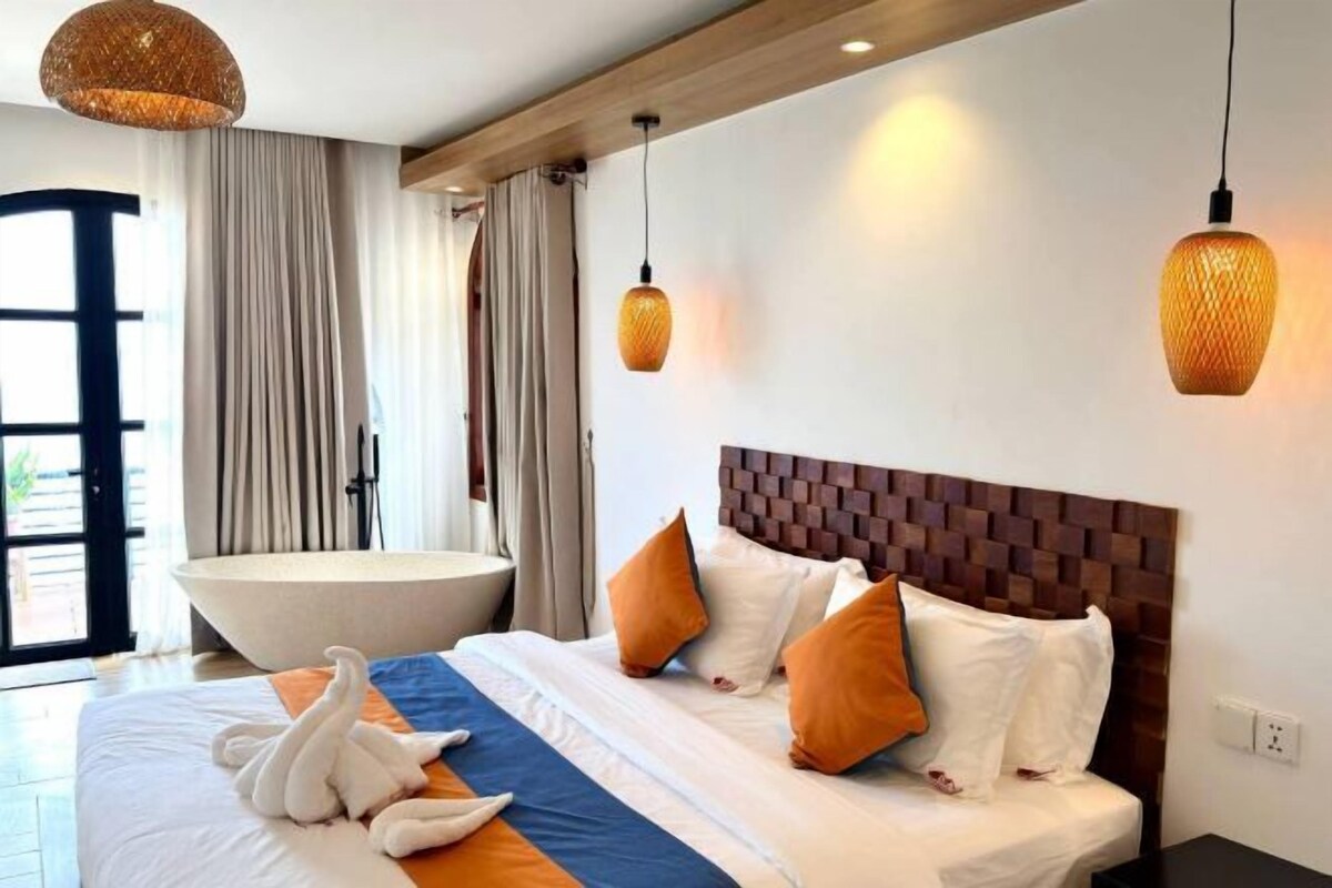 Una habitación de hotel con una cama grande, una bañera y techo de madera.
