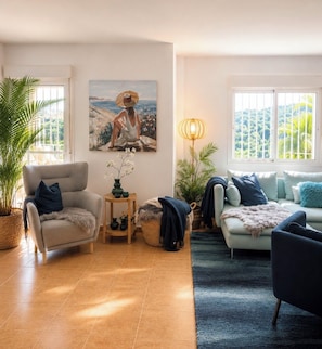 Uma sala de estar com sofá, poltrona e um quadro na parede.