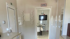 A modern kitchen with white cabinetry, a wooden floor, and a sign above the door.