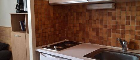 Cocina compacta con encimera blanca, estufa integrada, un lavabo y un refrigerador Frigelux.