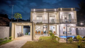 Et moderne hus med to etager, en overdækket terrasse, swimmingpool og veloplyst facade.