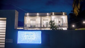 En moderne villa med balkon, oplyst skilt og udsigt til nattehimlen.