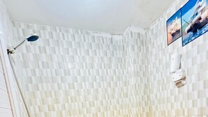 Une salle de bain équipée d’une douche, de toilettes et d’un distributeur de savon fixé au mur.