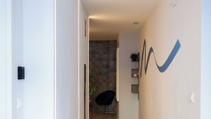 Ein moderner Flur mit Holzboden, einem schwarzen Stuhl und einer Steinwand im Hintergrund.