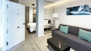 Ein modernes Hotelzimmer mit einem grauen Sofa, einem schwarzen Couchtisch und einem Wellenbild an der Wand.