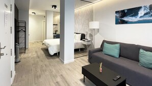 Ein modernes Hotelzimmer mit Bett, einer Couch, einem Couchtisch und einem Bild an der Wand.