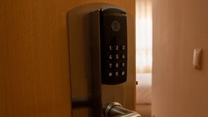 A modern door with a numeric keypad lock and a metallic handle. - HOSTAL AGORA (Novetlè)