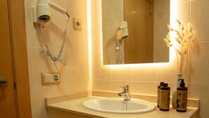 A bathroom with a sink, mirror, hairdryer, and towel rack. - HOSTAL AGORA (Novetlè)