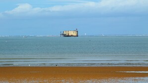 Eine Küstenlandschaft mit einem Sandstrand und einem Gebäude in der Ferne auf einem Steg.
