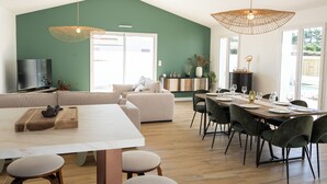 Ein modernes Wohnzimmer mit Essbereich, einer Couch, einem Fernseher und einem großen Fenster.