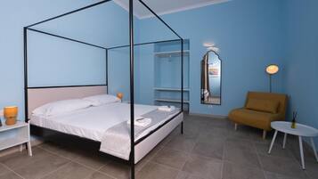 Une chambre à coucher avec un lit à baldaquin, une table de chevet, une chaise, une petite table et un miroir au mur.