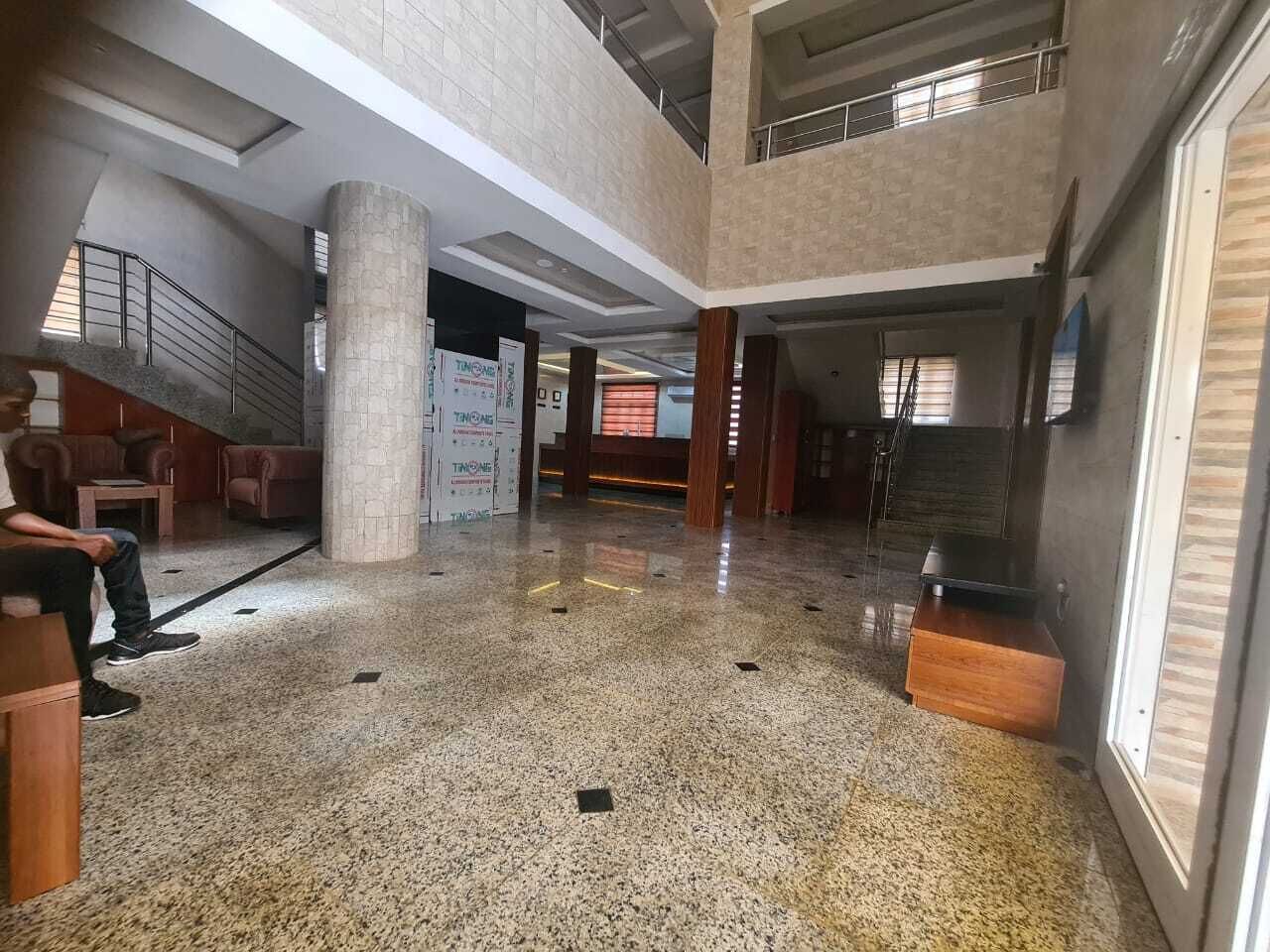 A spacious lobby with a polished floor, a staircase, and seating areas.