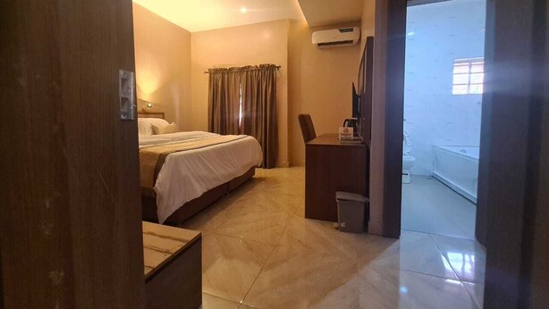 Une chambre d’hôtel avec un lit, un bureau et une salle de bain, visibles à travers une porte ouverte.