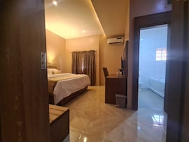 Una habitación de hotel con una cama, un escritorio y un baño visible a través de una puerta abierta.