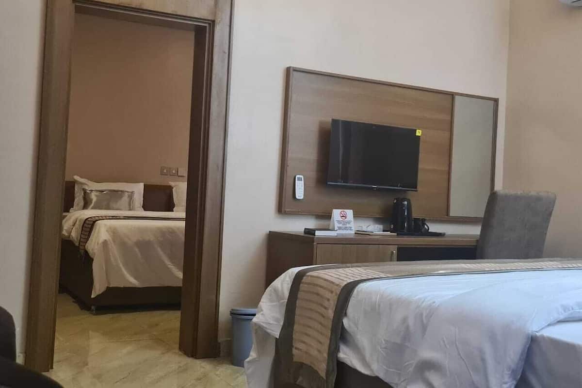 Une chambre d’hôtel équipée d’un lit, d’un bureau, d’une chaise, d’une télévision et d’un miroir.