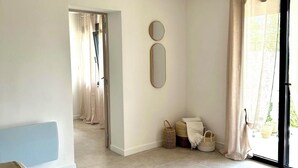 A spacious room with a large sliding glass door leading to an outdoor area, a light-colored tiled floor, and a modern light fixture with three bulbs.