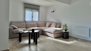 A modern living room with a sectional sofa, a coffee table, and a potted plant.