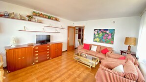 A living room with a wooden cabinet, a television, a striped sofa, and a coffee table. - Beach apartment, in front of the sea! (Caldes d'Estrac)