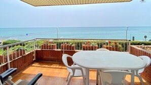 A balcony with a white table and chairs, overlooking a beach. - Beach apartment, in front of the sea! (Caldes d'Estrac)