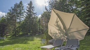 A campsite with two metal chairs and a large beige canopy.
