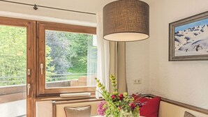 A dining area with a round table, a vase of flowers, and a painting on the wall.