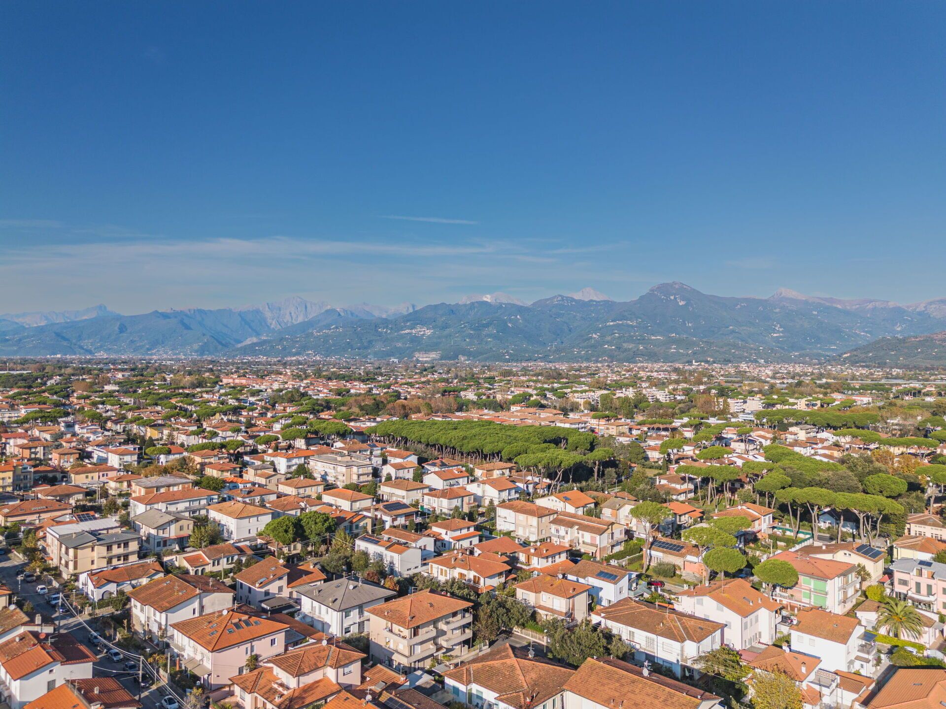 Un quartiere residenziale con un fitto gruppo di case, alcune dotate di pannelli solari, con una catena montuosa sullo sfondo.