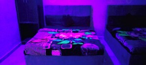 Ein Zimmer mit einem Bett mit bunter Bettwäsche, einem Fenster mit Blick und einer Wand mit dekorativem Muster.