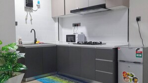 Une cuisine moderne avec des meubles gris, un plan de travail blanc, un four à micro-ondes encastré, une cuisinière à gaz et un réfrigérateur.