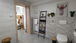 A modern bathroom with a toilet, sink, and shelves with plants.