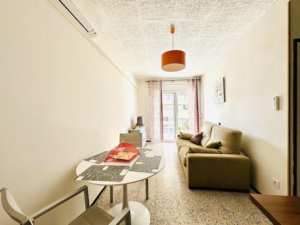 A modern living room with a sofa, a table with a red umbrella, and a patterned rug.