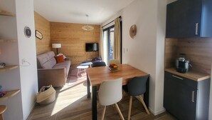 Un espace de vie compact comprenant un canapé, une table à manger, un téléviseur et une kitchenette.