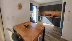 Une cuisine moderne avec des meubles de couleur sombre, un plan de travail en bois et un four encastré.
