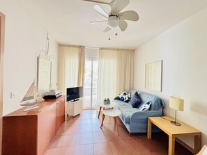 Una sala de estar moderna con un sofá, una mesa de centro, un televisor y un ventilador de techo.