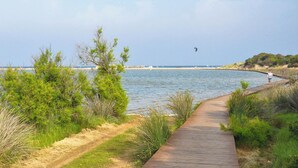 A wooden boardwalk leading to a beach with sparse vegetation and a clear sky. - Villa Bithia SaBratza Vacanze (Domus de Maria)